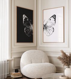 a white chair sitting next to a table in a room with paintings on the wall