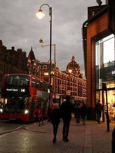 two double decker buses parked on the side of a street next to tall buildings at night