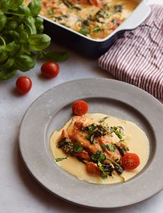 a white plate topped with food next to a pan filled with vegetables and sauce on top of a table