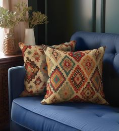 two pillows sitting on top of a blue couch next to a vase filled with flowers