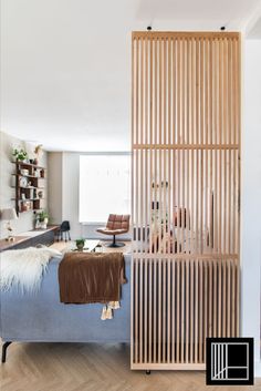 a living room with a blue couch and wooden slats on the wall behind it