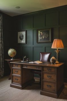 a desk with a lamp and pictures on the wall behind it in a green room