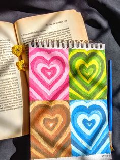 an open book with four different colored hearts on it next to a pencil and marker