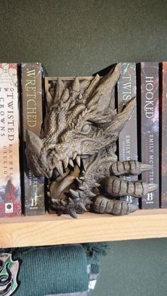 a book shelf with books and a dragon head on it's back end, in front of a green wall