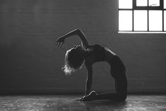 a woman is doing yoga on the floor in front of a brick wall and window