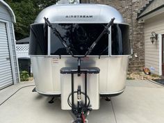 an rv parked in front of a house with a bike attached to the side of it