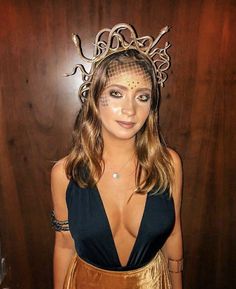 a woman wearing a veil and gold dress posing for a photo in front of a wooden wall