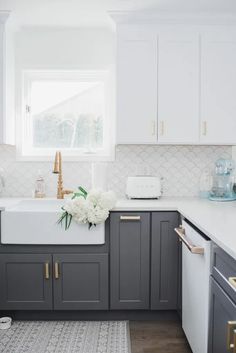 a kitchen with gray cabinets and white counter tops is pictured in this image, there are flowers on the window sill