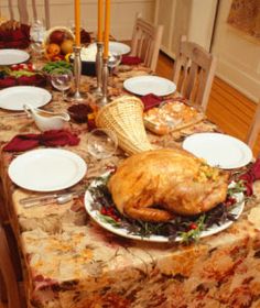 a large turkey sitting on top of a table next to white plates and silverware