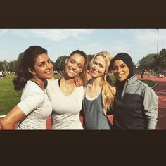 four young women are posing for a photo on a tennis court in the daytime time