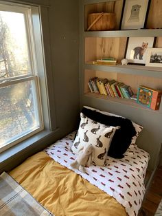 there is a bed with two pillows and a stuffed animal on it in front of a window