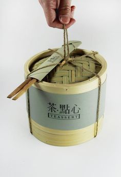 a hand holding a string over a bamboo container