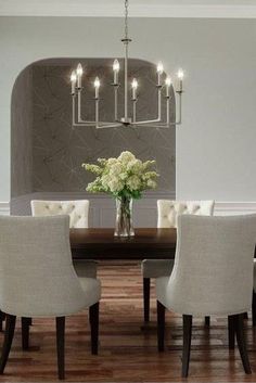 a dining room table with white chairs and a chandelier