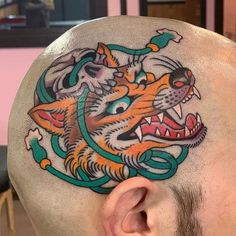 a man with a tattoo on his head has a tiger and snake design on it