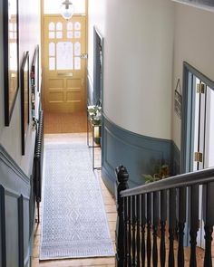 an entryway leading to a yellow door in a house with black railings and wood flooring