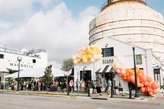 many people are standing in front of a building with balloons attached to the side of it