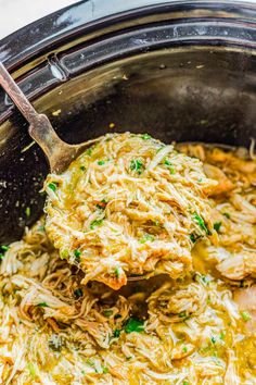 a spoon full of shredded chicken in a slow cooker