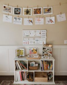 there is a book shelf with many books on the wall and pictures hanging above it