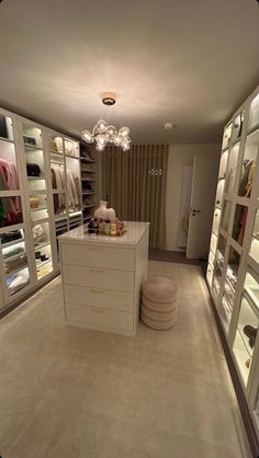 an empty walk - in closet with lots of shelves and lights on the ceiling, filled with clothes