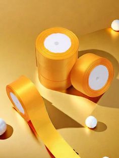 two rolls of yellow tape sitting next to each other on top of a gold surface