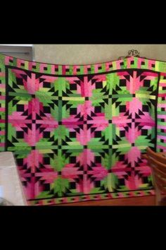 two women standing next to a large quilt