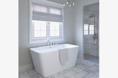 a white bath tub sitting next to a window in a bathroom under a chandelier