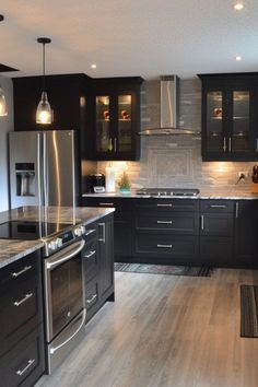 a large kitchen with black cabinets and stainless steel appliances, including an island countertop