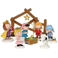 a group of figurines that are standing in front of a nativity scene