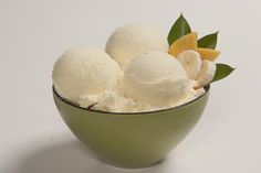 three scoops of ice cream in a green bowl on a white surface with leaves