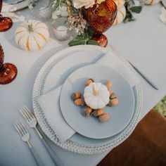 a white plate topped with a small pumpkin next to other plates and utensils