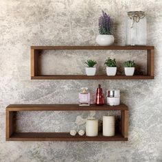 two wooden shelves with plants and candles on them in front of a concrete wall background