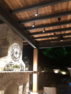 an outdoor fireplace with lights on it and a clock mounted to the wall above it