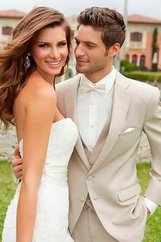 a man and woman in formal wear standing next to each other on the grass with their arms around each other