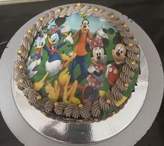 a mickey mouse birthday cake on a silver platter with an image of goofy and friends