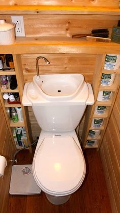 a small bathroom with wood paneling and white toilet in the corner next to shelves