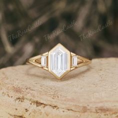 a gold ring with an emerald cut diamond in the center on top of a rock