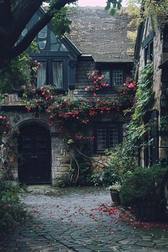 an old stone house with red flowers growing on it's windows and door way