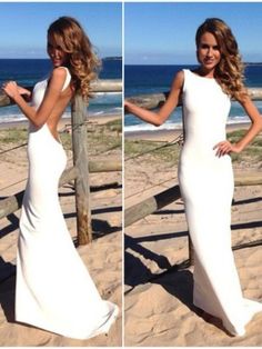 a woman standing on top of a sandy beach wearing a white dress and holding her hand out