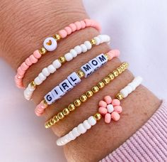 four different bracelets with the word girl mom written on one side and flower charms on the other