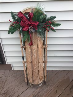 a sled decorated with holly and pine cones is sitting on a porch next to a house