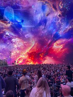 a large group of people standing in front of a colorful sky filled with stars and planets