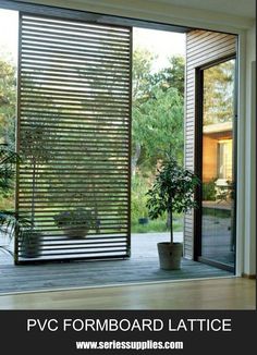 an open sliding glass door with potted plants on the outside and wooden flooring