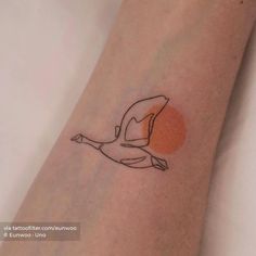 a small tattoo on the arm of a woman with a bird flying over it's head