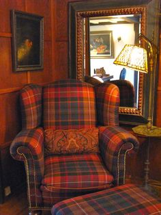 the chair is upholstered in plaid and has an intricately decorated armrest