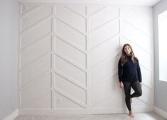 a woman standing in front of a wall with white chevroned panels on it