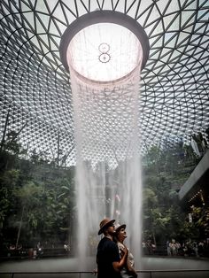 couple standing in front of the rain vortex at the jewel in Singapore Changi Airport Light Show, Travel Insurance