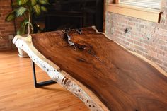 a wooden table sitting on top of a hard wood floor next to a brick wall