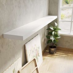 a white shelf sitting next to a potted plant on top of a wooden floor