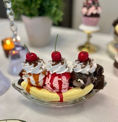 an ice cream sundae with cherries and whipped cream on top sits on a plate