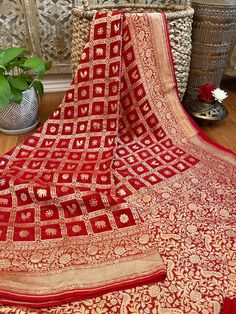 An exquisite pure khaddi georgette saree in a rich deep red shade with golden zari jaal benarasi work in kadua style. This saree is truly stunning. The pallu and border has dense floral and fauna designs and the gold really stands out beautifully. The fabric is extremely soft and drapes really well. It has a great fall and is very comfortable. The gorgeous animal motifs with the intricate borders create a very rich and royal look, perfect to add to your wedding trousseau or for any special occas Ceremonial Red Katan Silk Saree, Red Georgette Saree With Motifs, Red Georgette Dupatta With Zari Weaving, Red Ceremonial Saree With Zari Weaving, Red Motif Saree For Ceremonial Occasions, Red Saree With Zari Weaving For Ceremonial Occasions, Ceremonial Red Saree With Motifs, Ceremonial Red Motifs Saree, Red Silk Dupatta For Ceremonial Use